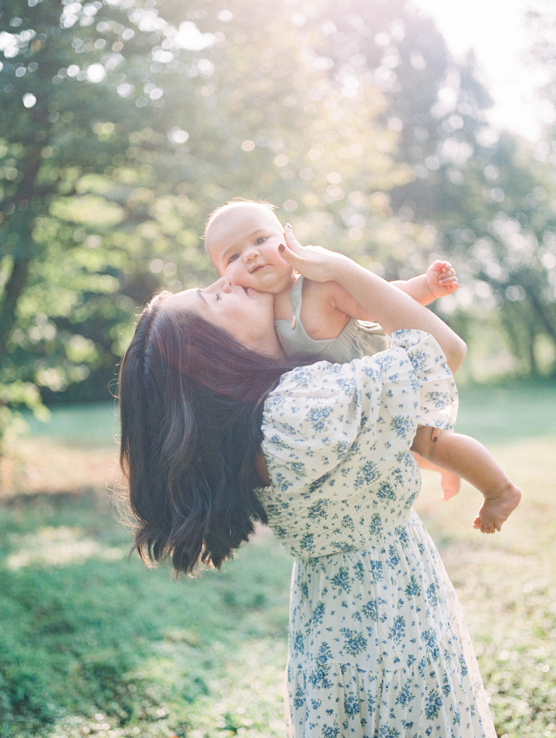 Mom in Nothing Fits But dress holding baby boy and kissing him on the cheeck by Richmond Family Photographer